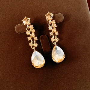 Detail of champagne gold drop earrings with pear-cut crystals on a velvet display