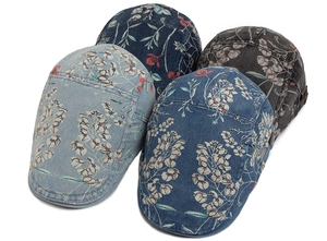 Close-up of four washed denim flat caps with vintage floral patterns and metal side buckles