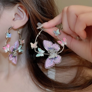 Detail of silver hoop earrings featuring colorful fabric butterflies and crystals