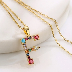 Macro shot of letter F pendant with colorful gemstones on a gold-plated necklace