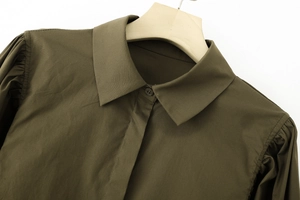 Detailed view of puff shoulder design and turn-down collar on olive green cotton shirt