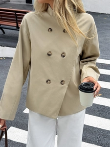 Detail of khaki double-breasted short coat jacket with button closure in outdoor setting