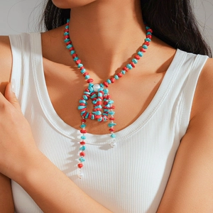 Detail of bohemian necklace featuring red stones, turquoise beads and woven bow design