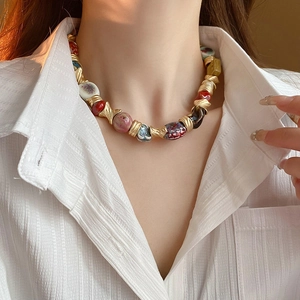 Detailed shot of ethnic ceramic floral beads on a vintage gold necklace for women