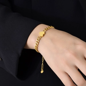 Gold stainless steel curb chain bracelet with heart pendant on model wrist