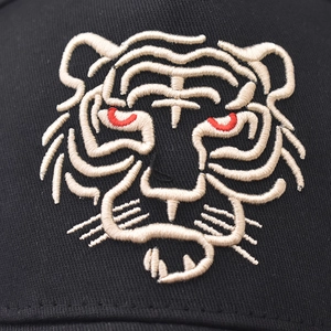 Close-up of intricate tiger head embroidery on a premium black cotton baseball cap