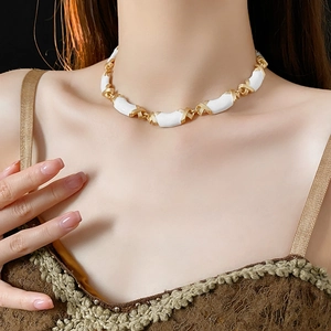 Detail of vintage enamel necklace in gold and white worn by a professional model