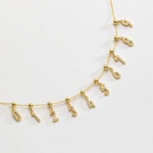 Macro detail of gold S925 silver bracelet featuring sparkling pavé crystal number charms