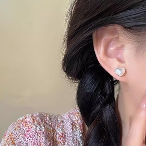 Close-up of heart-shaped pearl stud earring with iridescent white mother-of-pearl finish