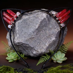Detailed macro view of black cat ear headband with red crystals on a natural stone base