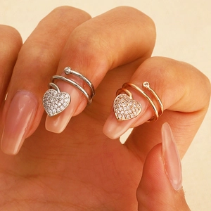 Detail of heart-shaped zircon nail rings in silver and rose gold finishes on a model