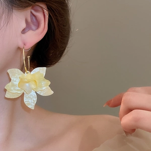Gros plan d'une grande boucle d'oreille fleur en résine jaune pâle sur un mannequin