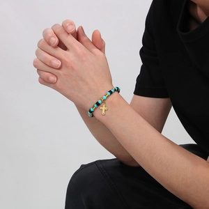 Bracelet bohème perlé avec croix en bleu, noir et doré porté sur le poignet