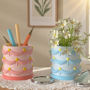 Detail of pink and blue cake-shaped cylindrical resin organizer with embossed ribbon patterns
