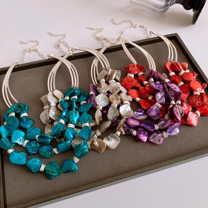 Detailed top view of bohemian layered necklaces with colorful shell pendants in a tray
