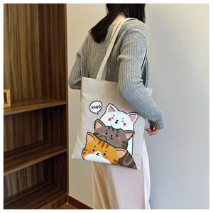Detail of canvas tote bag featuring cute cartoon cats and a miao speech bubble print