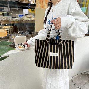 Detail of canvas tote bag with black and yellow vertical stripes and a white woven label