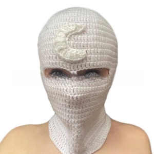Detail of white knit balaclava mask featuring a crescent moon emblem and eye cutouts