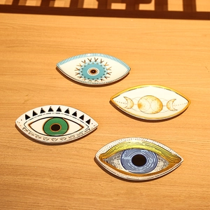 Macro view of four assorted ceramic evil eye jewelry trays with gold rim on wood