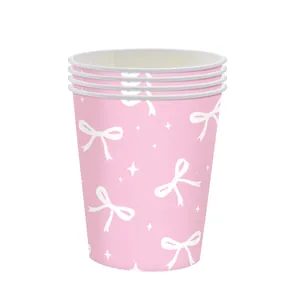 Close-up of pink disposable paper cups with white bow and star patterns for party decor