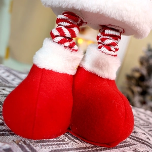Close-up of festive red and white striped knit legs with felt boots on Christmas doll