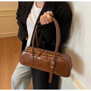Detail of caramel brown baguette bag featuring smooth leather and silver zipper hardware