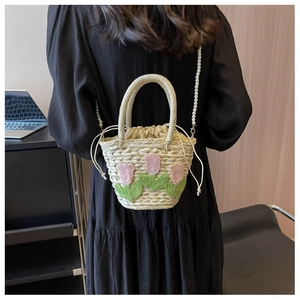 Detail der Stroh-Eimertasche mit Tulpenstickerei und eleganter Perlenkette-Riemen