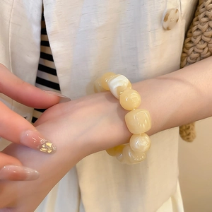 Détail du bracelet en acrylique crème avec perles rondes et carrées sur le poignet