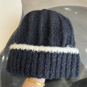 Détail de la texture d'un bonnet en maille épaisse avec rayure blanche sur fond noir