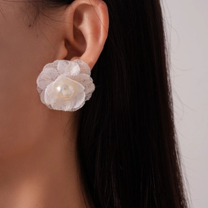 Detailed view of lace flower earring with a central pearl on a model's ear