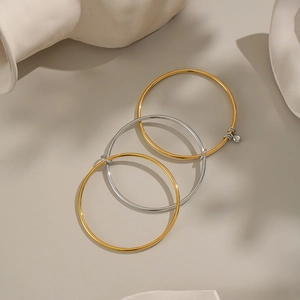 Detail of three-layer mixed gold and silver bangle with zircon charm on ceramic dish