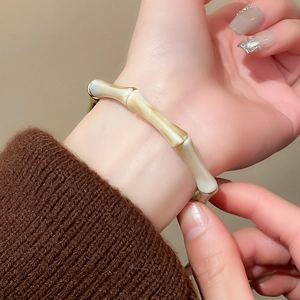 Macro view of vintage-style resin bamboo bangle paired with autumn knitwear sleeve
