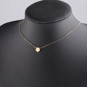 Detail of a minimalist gold flower pendant necklace displayed on a black neck mannequin