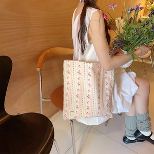 Détail du sac cabas en toile à fleurs avec anses roses dans un décor vintage