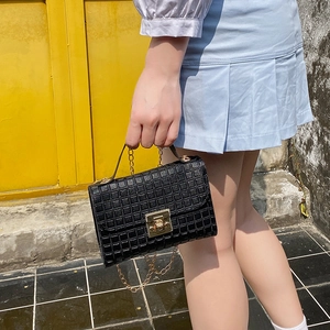 Detail of black quilted leather handbag showing the gold clasp and metal chain strap