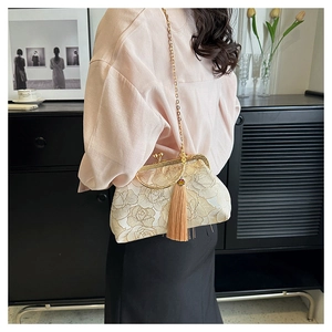 Detail view of floral embroidery on a vintage shell bag with a gold metal ring handle