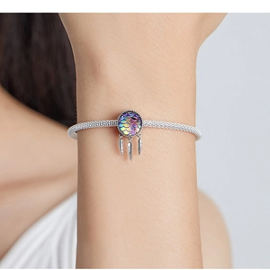 Macro shot of a silver dreamcatcher charm with colorful scales and feather pendants