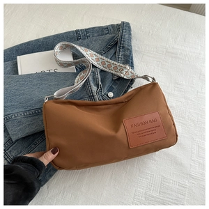 Brown nylon crossbody bag featuring a wide ethnic pattern strap on white fabric