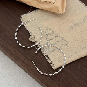 Detailed macro view of 925 sterling silver twisted hoop earrings on rustic linen background