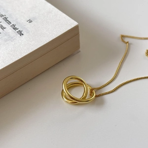 Detailed view of triple gold interlinked rings necklace on an open vintage book background