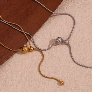 Detail of gold and silver Y-shaped snake chains with sleek beads on textured background