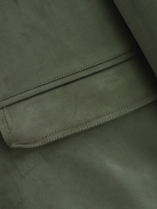 Macro detail of dark olive green faux suede jacket showing precise stitching on pocket flap
