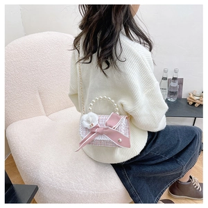 Pink tweed bag with pearl handle, ribbon bow, and camellia charm shown on a chair