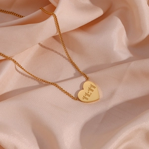 Close-up of golden heart pendant with 11:11 engraving on champagne satin background