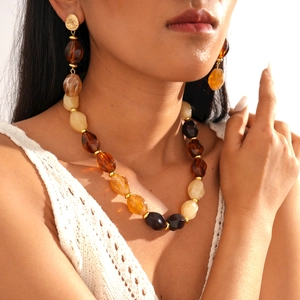 Close-up of retro amber acrylic oval beaded necklace and earring set on a model