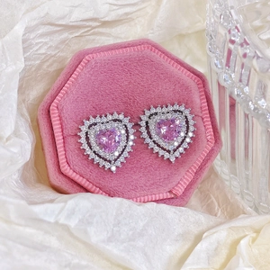 Detailed macro view of pink heart zircon earrings in a luxury velvet jewelry box