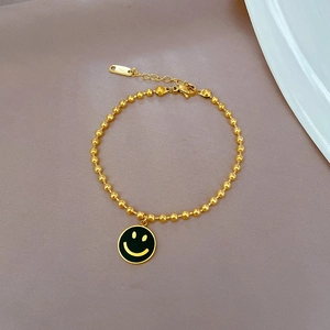 Nahaufnahme des goldenen Edelstahl-Perlenarmbands mit gelbem Smiley-Anhänger