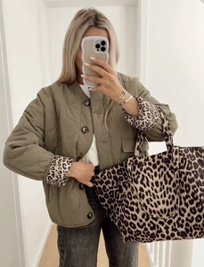 Detailansicht der olivgrünen Steppjacke mit Leopardenmuster-Futter und passender Tragetasche