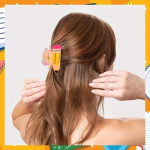 Gros plan d'une pince à cheveux créative en forme de crayon sur une queue de cheval brune
