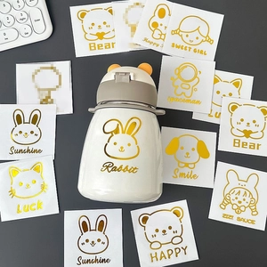Cute cream kids thermos with cartoon metal stickers and yellow ear lid on dark desk